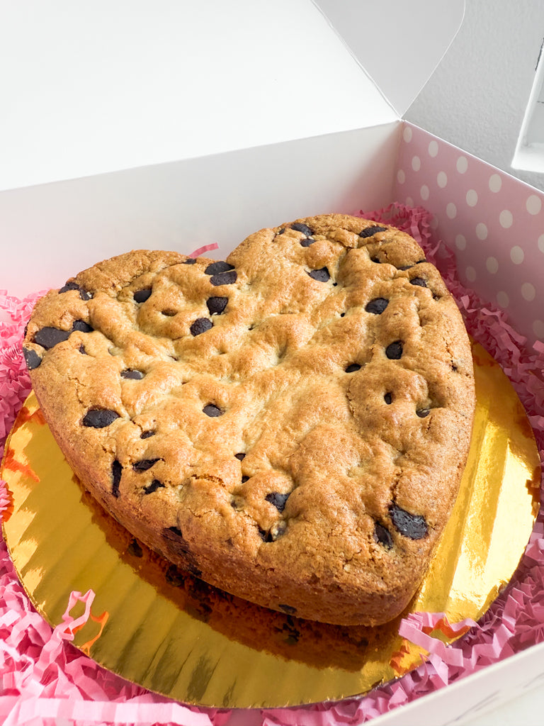 Heart-shaped chocolate chip cookie in a box with pink polka dot interior